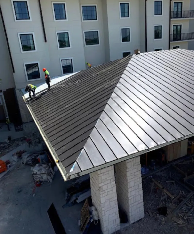 Crew installing standing seam metal roof panels on a commercial project in North Valley